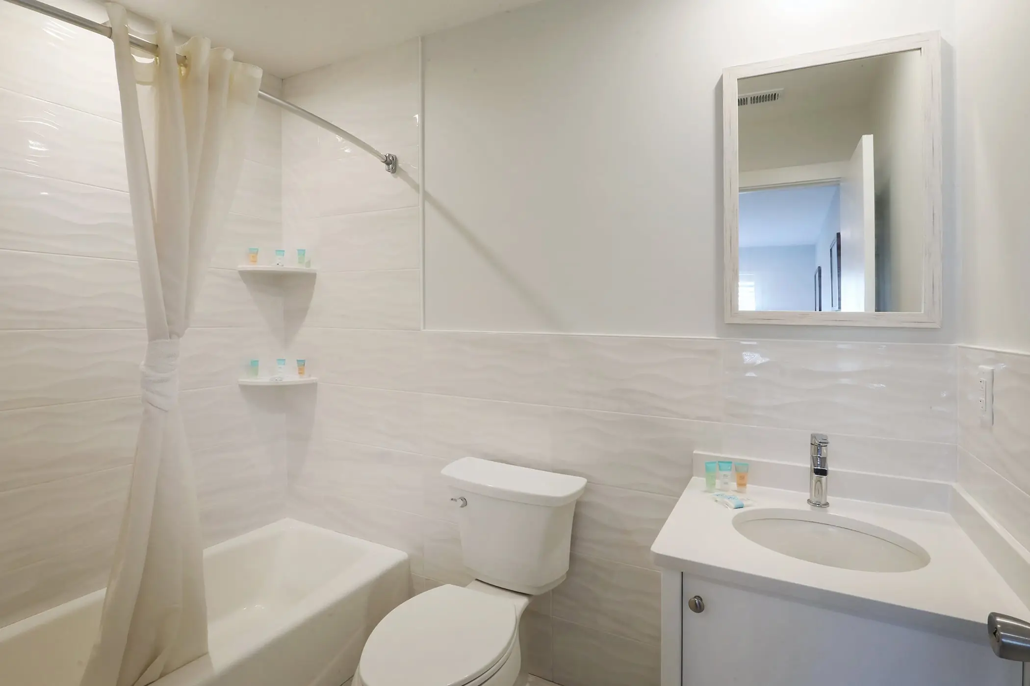 The bathroom of a Type 10 Townhouse Motel Room at the Matador, with a tub and shower, toilet and vanity