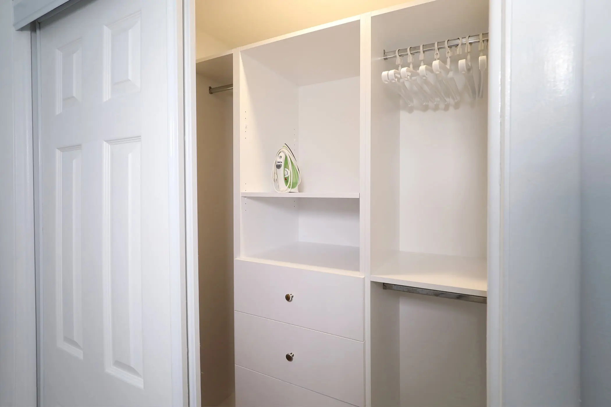 The closet in a Type 10 Townhouse Motel Room at the Matador, with shelves, drawers, hangers and an iron