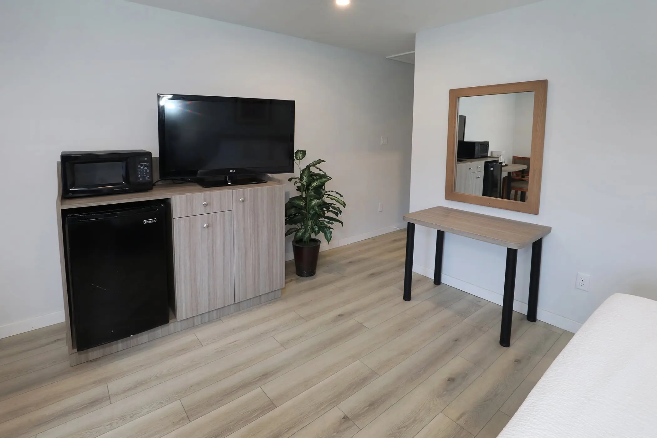 A desk with a wall mirror beside the TV cabinet in a Type 10 Townhouse Motel Room at the Matador