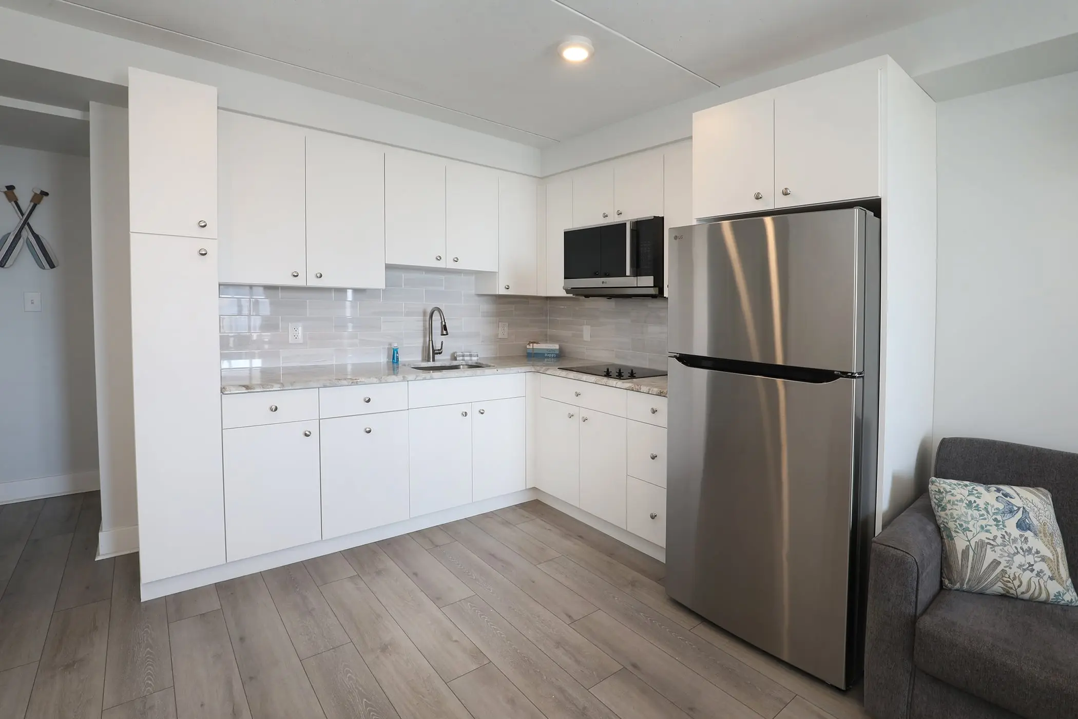 The kitchen in a Type 8 Two-Bedroom Unit at the Matador, with white cabinets, a stainless steel refrigerator and a microwave