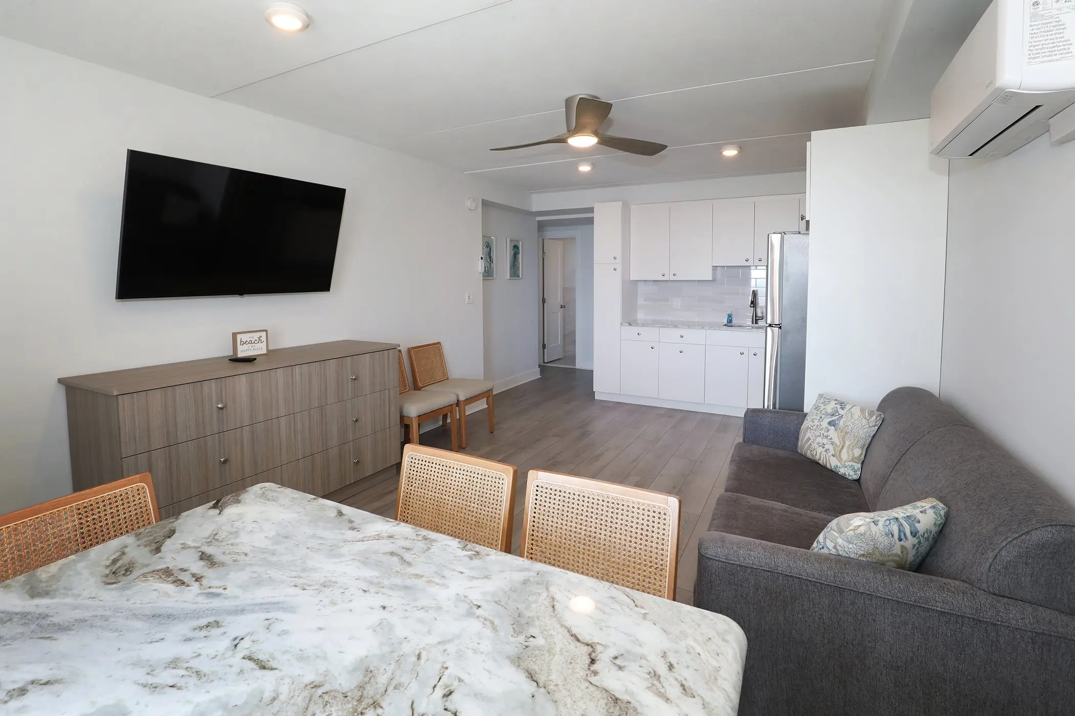 Looking across a Type 8 Two-Bedroom Unit at the Matador from the dining table to the sofa, wall-mounted TV and open kitchen