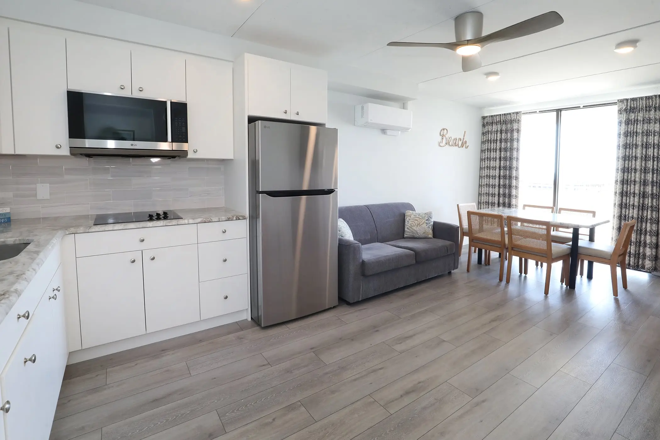 A Type 8 Two-Bedroom Unit at the Matador: an L-shaped kitchen with a full-size refrigerator, opening onto the sofa and dining table by the windows